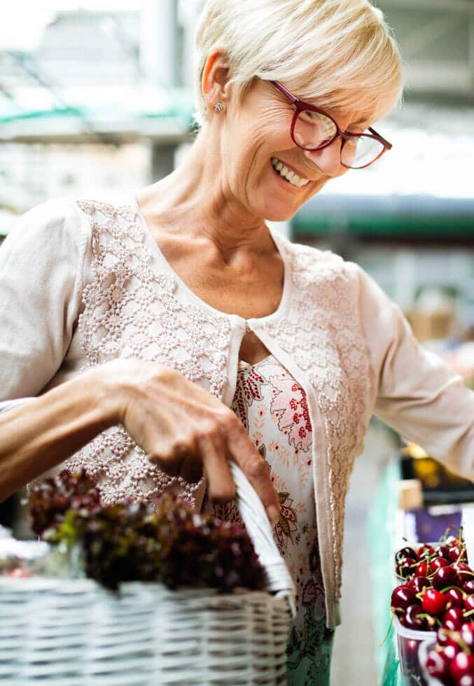 Lady wearing glasses holds a basket while buying cherries at a market in Peoria, Arizona.